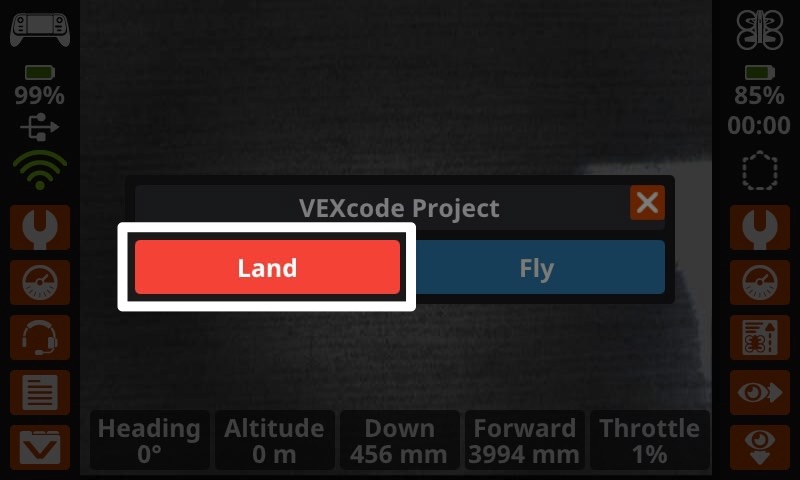 A screenshot of the prompt on the Controller screen, showing the project name at the top with two button options - to the left reads Land and to the right reads Fly. The Land button is highlighted indicating what to select to stop the project.